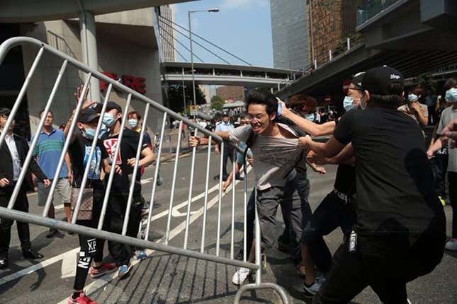 A group of unidentified men pulls a pro-democracy protester from a barricade.