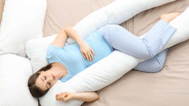 Pregnant person sleeping with pregnancy pillow