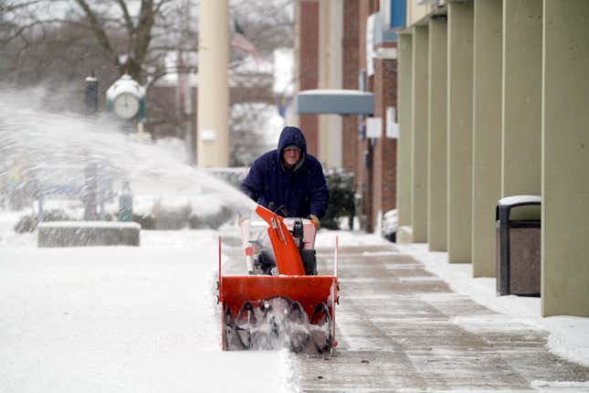 A man cleans off snow in front of Berkshire Commons on South Street in Pittsfield, Massachusetts, on Tuesday, Feb. 28, 2023.