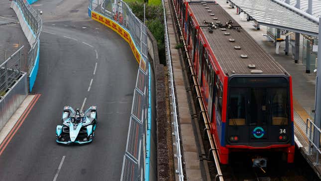 A Formula E car drives alongside a London train