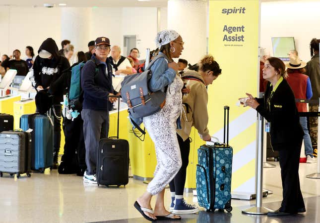 An agent assists as people gather at the check-in area for Spirit Airlines at Los Angeles International Airport (LAX) on June 1, 2023 in Los Angeles, California.  More than 40 percent of Spirit Airlines flights nationwide were delayed earlier today following a technical issue with its app, website and airport kiosk.