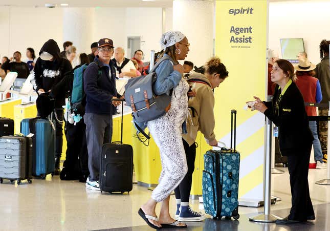 Un agente ayuda mientras las personas se reúnen en el área de check-in de Spirit Airlines en el Aeropuerto Internacional de Los Ángeles (LAX) el 1 de junio de 2023 en Los Ángeles, California.  Más del 40 por ciento de los vuelos de Spirit Airlines en todo el país se retrasaron hoy debido a un problema técnico con su aplicación, sitio web y quioscos del aeropuerto.