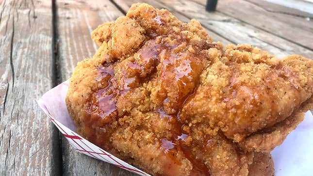 Honey-Chipotle Drizzling Sauce on top of fried chicken in cardboard bowl on wood surface