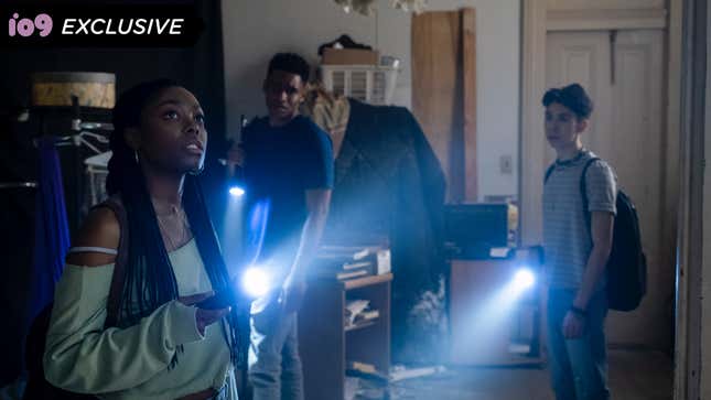 A young woman holds a flashlight in the foreground, along with two young men who are also holding flashlights.