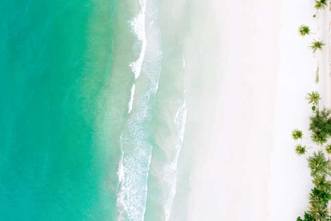 Vista aérea de una playa con arenas blancas y aguas verdosas