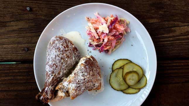Alabama White BBQ Sauce with chicken, slaw, and pickles on white plate atop wood surface