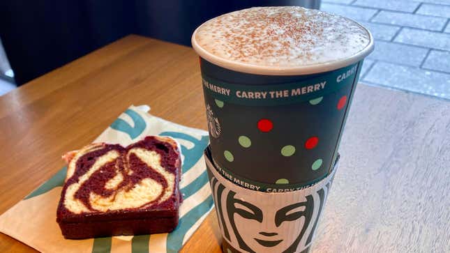 Slice of Red Velvet Loaf set on pastry bag on tabletop beside Starbucks Venti Pistachio Latte