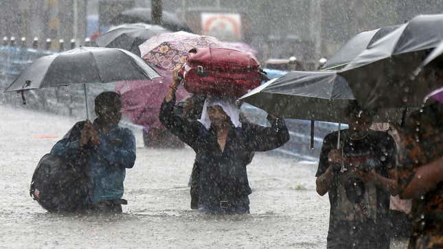 People navigate through a flooded street in Mumbai on Sept. 04.