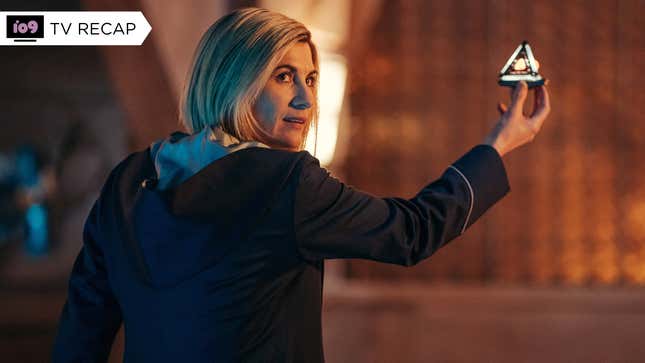 Jodie Whittaker's 13th Doctor has her back to the camera with her head turned and holds up a small, triangular beacon device.