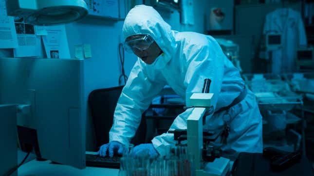 A man in a hazmat suit leans over a computer in The Sadness