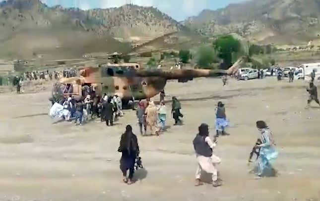 A number of people crowd around military helicopters transporting injured away from quake-affected areas in Afghanistan. 