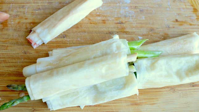 Vegetables wrapped in phyllo dough are stacked together on a cutting board.