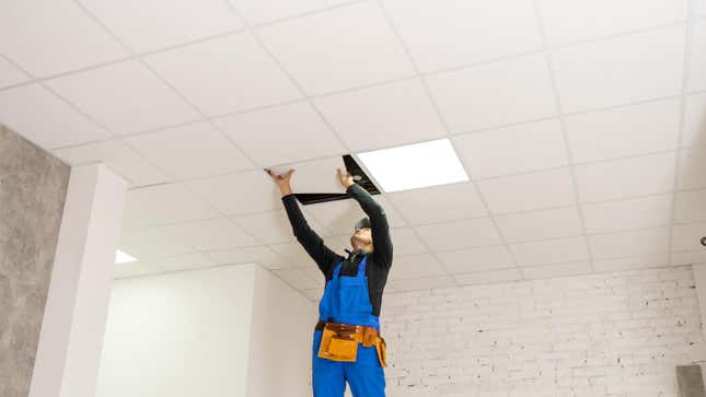 contractor installing a drop ceiling in a bright empty room