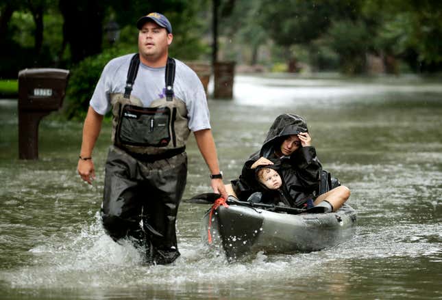 People evacuate a neighborhood inundated by floodwaters from Tropical Storm Harvey on Aug. 28, in Houston.