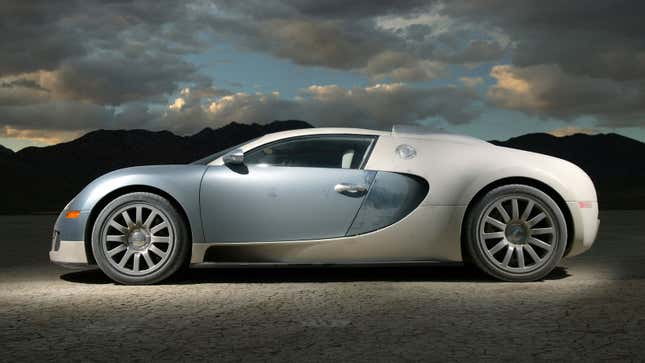 A photo of a blue and white Bugatti Veyron parked on a lake bed. 