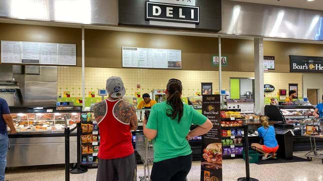Two customers waiting in line at the grocery store deli