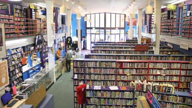 The scarecrow video store in Seattle, Washington with multiple shelves full of dvds and one customer checking out a video at the counter.