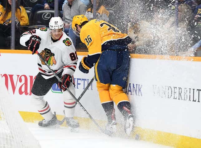 Mar 16, 2023; Nashville, Tennessee, USA; Nashville Predators left wing Cole Smith (36) hits the board as he tries to play the puck against Chicago Blackhawks defenseman Caleb Jones (82) during the first period at Bridgestone Arena.