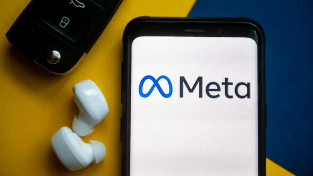 The Meta logo displayed on a smartphone next to wireless earphones and... car keys, for some reason. Used here as stock photo.