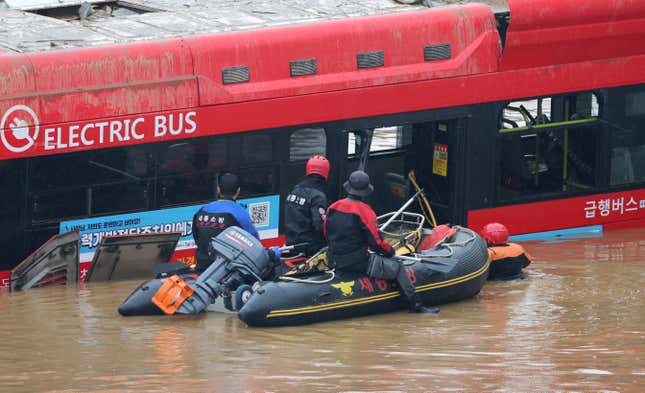 Rescuers conduct a search operation along a road submerged by floodwaters leading to an underground tunnel in Cheongju, South Korea, on July 16, 2023.