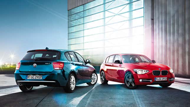 Two BMW 1 Series cars parked by a hanger 