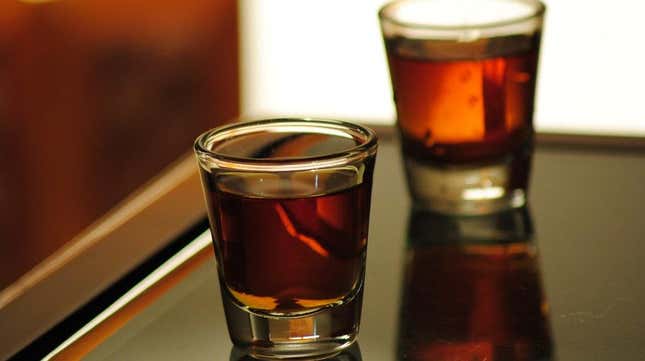 Two shots of deep mahogany brown whiskey shots on a wooden bar