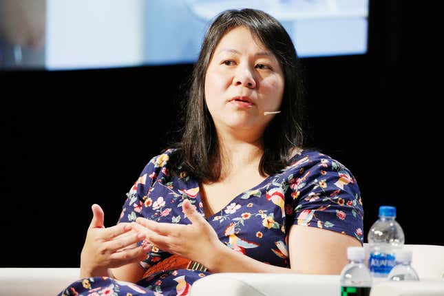 A portrait of Bo Young Lee seated while speaking on stage. 