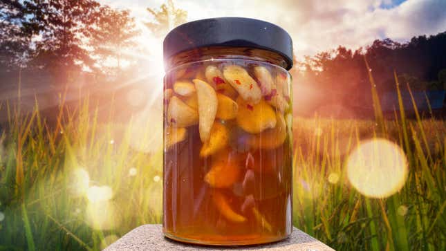 Jar of Honey-Fermented Garlic with summery grasses and sunlight in background