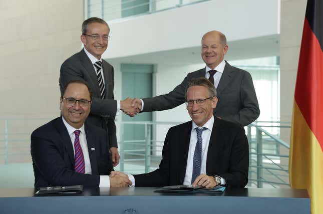 German Chancellor Olaf Scholz (R, behind) and Intel CEO Pat Gelsinger (L, behind) shake hands as State Secretary Joerg Kukies (front, R) and Intel board member Keyvan Esfarjani also shake hands after signing an agreement.