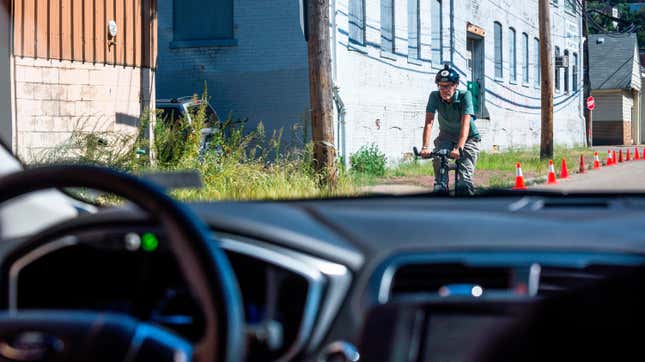 A bicyclist riding past an Uber self-driving car during a road test in Pittsburgh, Pennsylvania in 2016.