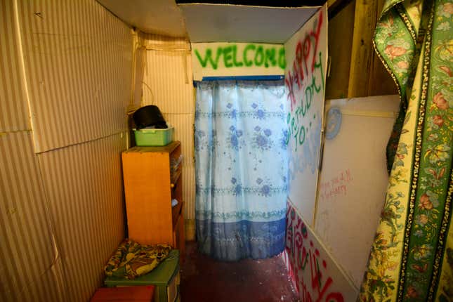 A refugee shack in Hong Kong with "Welcome" spray-painted over the doorway.
