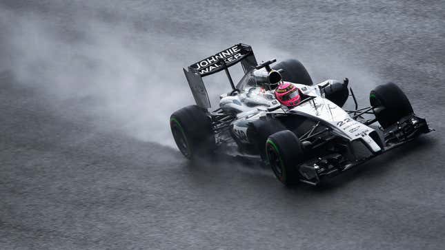 A photo of Jenson Button driving his 2014 McLaren F1 car in the rain. 