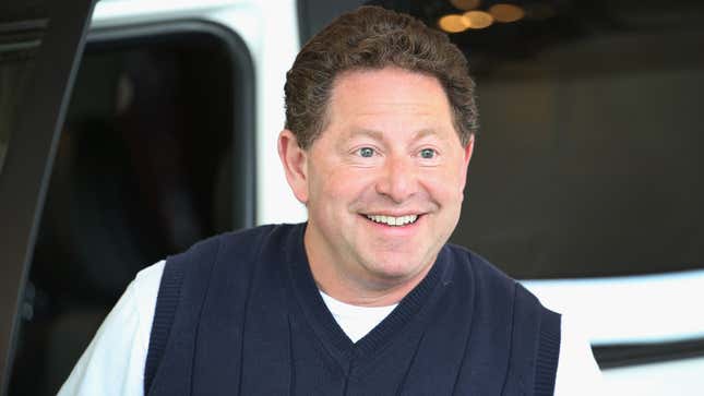 A portly man with short, curly hair smiles at an off-camera subject.