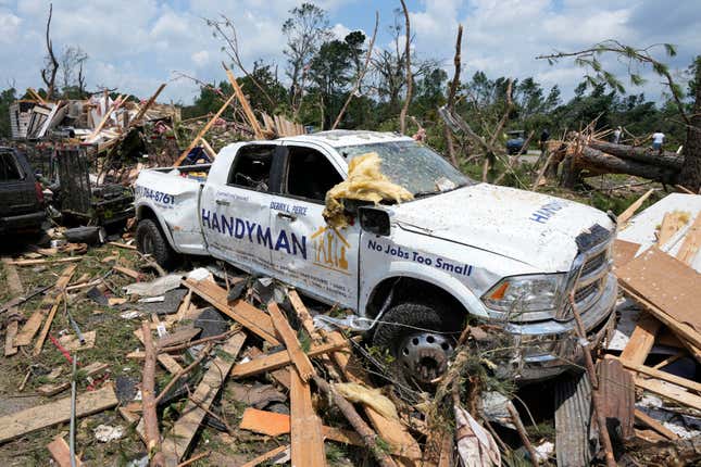 A damaged vehicle stands amid debris littering a home following a Sunday night tornado that swept through Louin, Mississippi on June 19, 2023. 