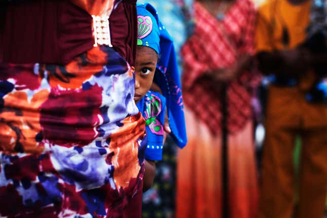 A girl from the African Hebrew Israelite community hides behind an adult during the Jewish holiday of Shavuot in the southern Israeli town of Dimona, on June 15, 2014.