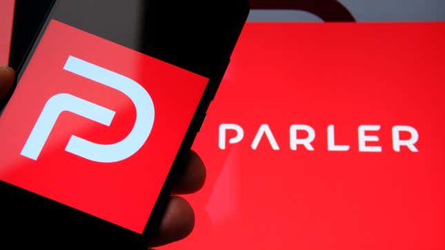 An image of Parler's red logo on a smartphone is seen against a Parler banner.
