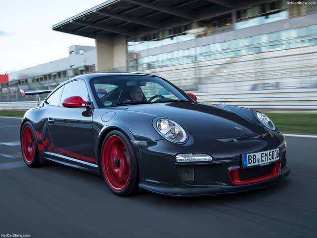 A grey and red Porsche 997 911 GT3 RS drives on track.