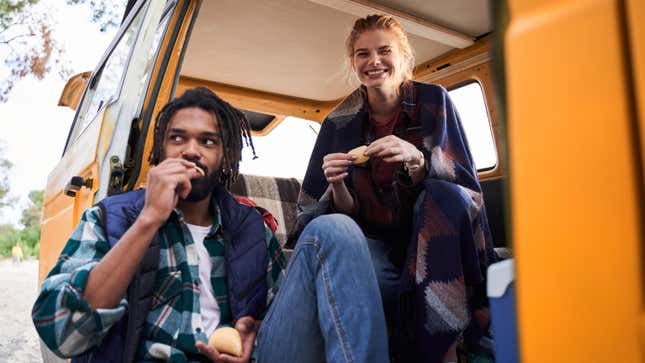 Man and woman eating in a van on a roadtrip