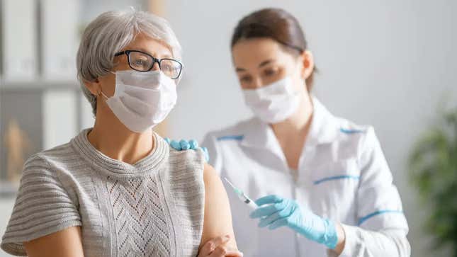 An older woman getting a vaccine from a nurse