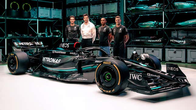 A photo of Lewis Hamilton, George Russell, Mick Schumacher and Toto Wolff stood next to a Mercedes F1 car. 