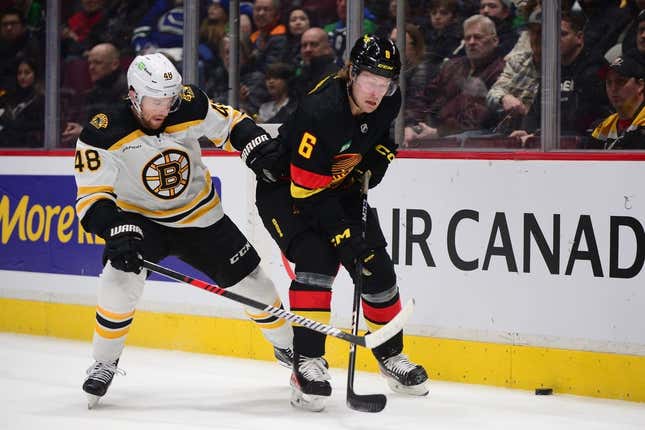 Feb 25, 2023; Vancouver, British Columbia, CAN; Vancouver Canucks forward Brock Boeser (6) battles for the puck against Boston Bruins defenseman Matt Grzelcyk (48) during the first period at Rogers Arena.