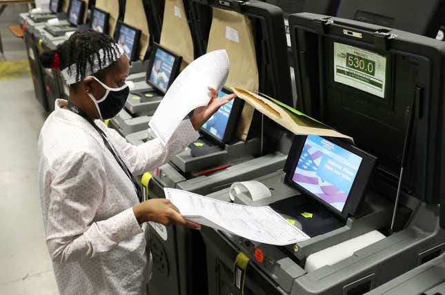  A Miami-Dade election worker feeds ballots into voting machines during an accuracy test at the Miami-Dade Election Department headquarters on October 14, 2020, in Doral, Florida. 