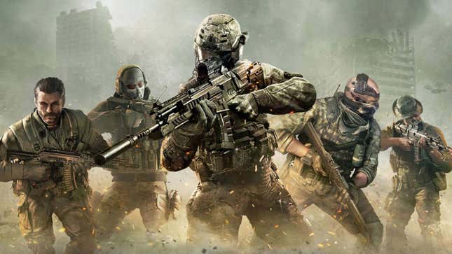 A group of five heavily armed soldiers stand together in a dusty environment. 
