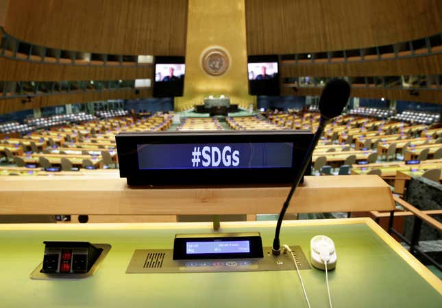 A view of empty desks at the UN General Assembly Hall with a screen that reads "#SDGs"