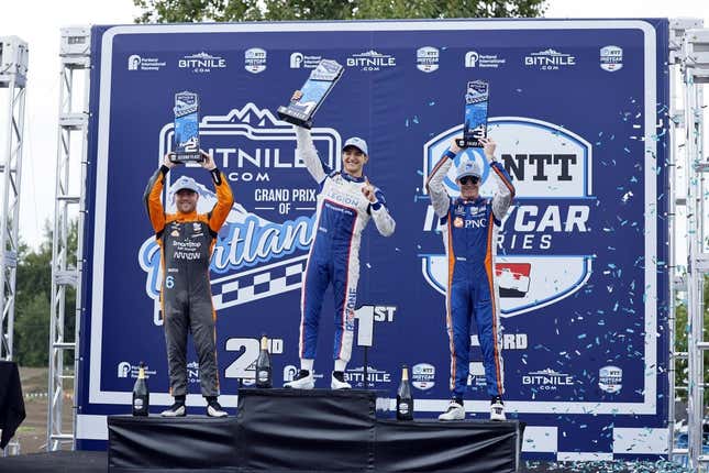 Sep 3, 2023; Portland, Oregon, USA; NTT Indy Car driver Alex Palou (center) lifts his first place trophy with second place finisher Felix Rosenqvist (left) and third place finisher Scott Dixon (right) at Portland International Raceway.