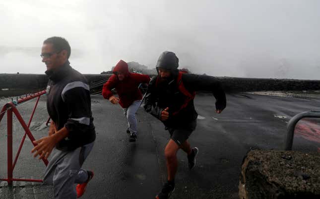 People run as waves hit the coast of Sao Mateus.