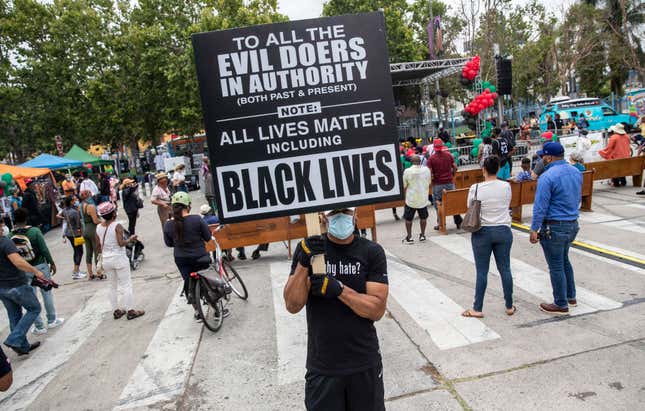Isadore Henry of Los Angeles holds a sign during the Juneteenth celebration on Friday, June 19, 2020, in Leimert Park, CA.