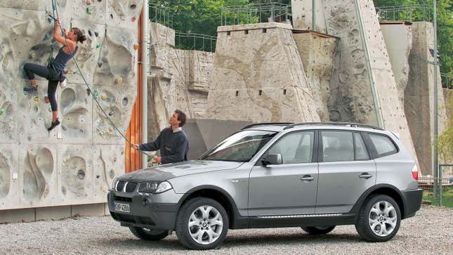 A photo of two people rock climbing near a BMW X3 SUV. 