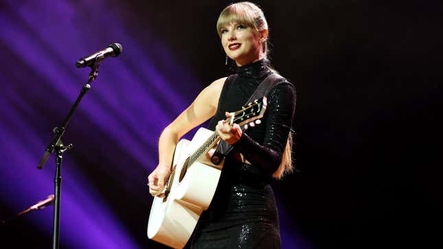 A photo of Taylor Swift playing a white guitar on stage. 
