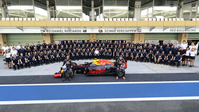 A photo of the 2016 Red Bull F1 team sat around a car in the garage. 